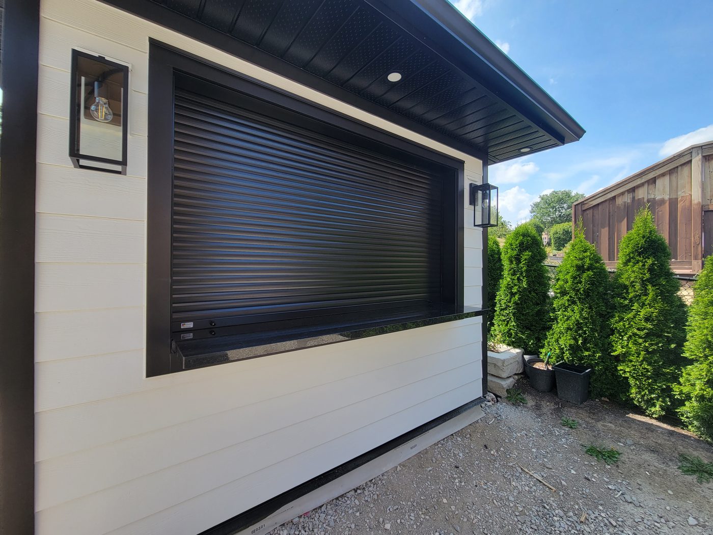 Dark aluminum security shutter closed over a large window opening
